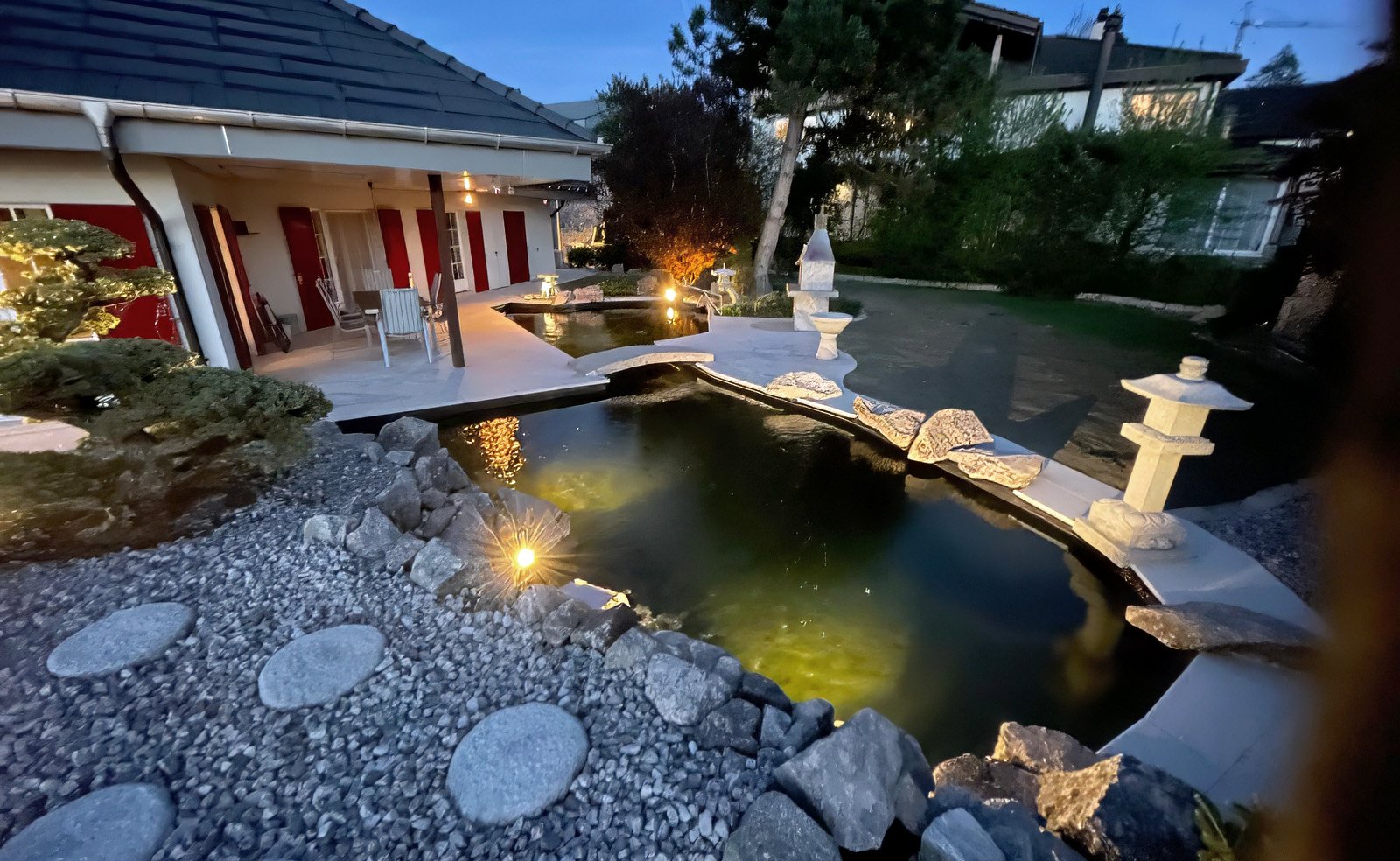 Hausgarten mit beleuchtetem Teich am Abend